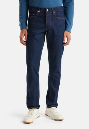 Blauwe spijkerbroek van denim met oranje stiksels, vijf zakken en een rechte pasvorm. Ontworpen met een knoop- en ritssluiting. Draag het met witte sneakers.