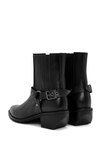 Zwarte leren enkelboots met een blokhak, voorzien van ribbel-elastische panelen, een decoratieve band met metalen accenten en een gladde afwerking.
