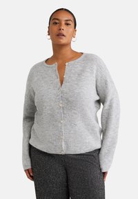 Grau gestrickte Strickjacke mit einem Henley-Ausschnitt und fünf hellen Holzknöpfen auf der Vorderseite. Weicher Stoff, lässige Passform und lange Ärmel.