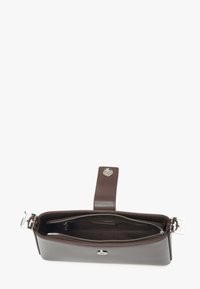 Smeđa kožna torba s glatkom površinom, zatvaranjem na zip, i odvojivim remenom. Unutrašnjost sadrži mekanu podstavu. Prisutni su srebrni dodaci.