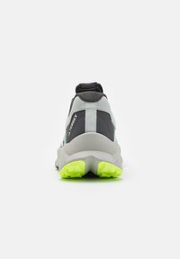 Zapatilla gris claro con acentos gris oscuro, parte superior texturizada, cuello acolchado y suela de un brillante color verde lima con un patrón antideslizante.
