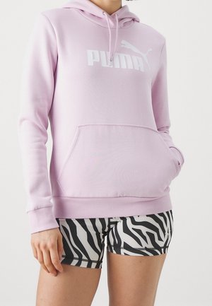 Sudadera con capucha Puma lavanda con bolsillo delantero combinada con pantalones cortos deportivos estampados de cebra en blanco y negro en una persona de pie.