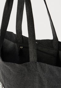 Fekete farmertáska két erős pánttal, belül cipzáras zsebbel a biztonságos tároláshoz. Puha tapintás, minimalista dizájn.