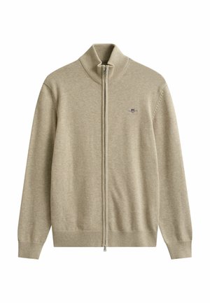 Suéter beige de cremallera completa con cuello, puños y dobladillo acanalados, con un pequeño logo bordado en forma de escudo en el pecho izquierdo.