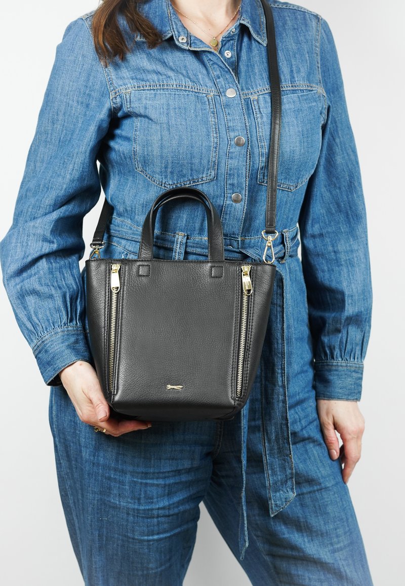 Zwarte leren handtas met bovenhandvatten en een afneembare schouderriem; heeft zilveren ritsen en een gestructureerd oppervlak.