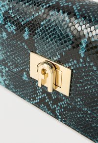 Μαύρο και μπλε φάκελος από δέρμα με σχέδιο φίδι, που διαθέτει κούμπωμα από μέταλλο σε χρυσή απόχρωση με ανάγλυφο λογότυπο και λεία υφή.