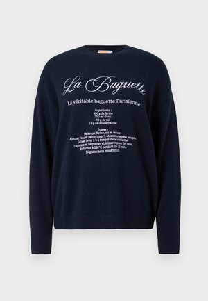 Navy sweater with white French text showing a Parisian baguette recipe including ingredients and baking instructions on the front.