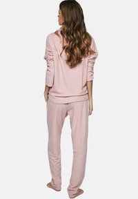 Lichtroze loungewear set bestaande uit een ontspannen sweatshirt en bijpassende joggerbroeken. Zacht materiaal met een effen textuur en eenvoudig ontwerp.