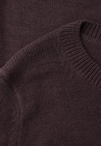 Pull en maille marron foncé avec col rond côtelé, montrant un gros plan sur la texture et le détail de la couture d'épaule.
