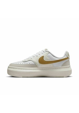 Zapatilla blanca con puntera perforada, swoosh dorado de Nike y suela texturizada. Presenta cordones planos y un cuello acolchado para mayor soporte.