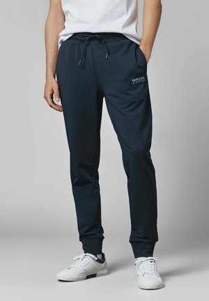 Navy sweatpants with an elastic waistband and drawstring, featuring side pockets and a small logo on the left thigh. Smooth fabric texture.