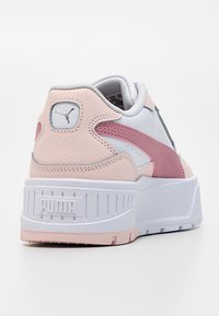 Weißer und pinker Puma-Sneaker mit dicker Sohle, strukturiertem Absatz und pinkem Seitenstreifen, gesehen von hinten und links.