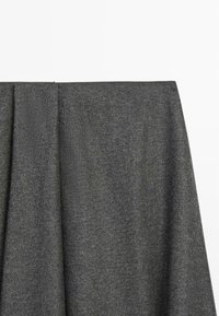 Tessuto grigio con una consistenza morbida, che mostra un delicato motivo melangiato. È drappeggiato, evidenziando la sua forma fluida e la qualità del materiale.