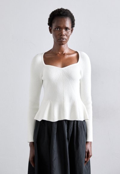 Pull en maille blanche à côtes avec manches longues, décolleté carré et bas peplum ; présente une texture verticale et un corsage ajusté.