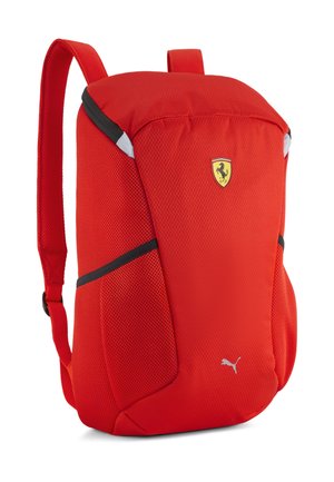 Lys rød rygsæk med Ferrari- og Puma-logoer, to skulderstropper og sorte accentlinjer på siderne, vist mod en hvid baggrund.