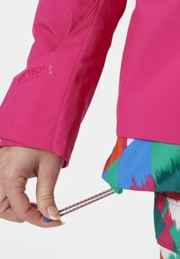 Felle roze jas met een gestructureerd oppervlak, voorzien van een logo en een gekleurde, patronenzoom. Verstelbare trekkoord met meerkleurige accenten.