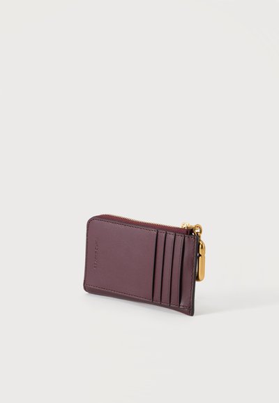 Porte-cartes compact en cuir marron foncé avec quatre emplacements pour cartes et une tirette de fermeture éclair dorée sur fond blanc.