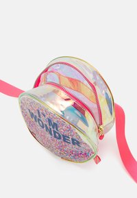 Zaino trasparente e rotondo con una tracolla rosa. Presenta un fondo glitterato con la scritta "I'M WONDER", doppi zip di chiusura e un design interno colorato.