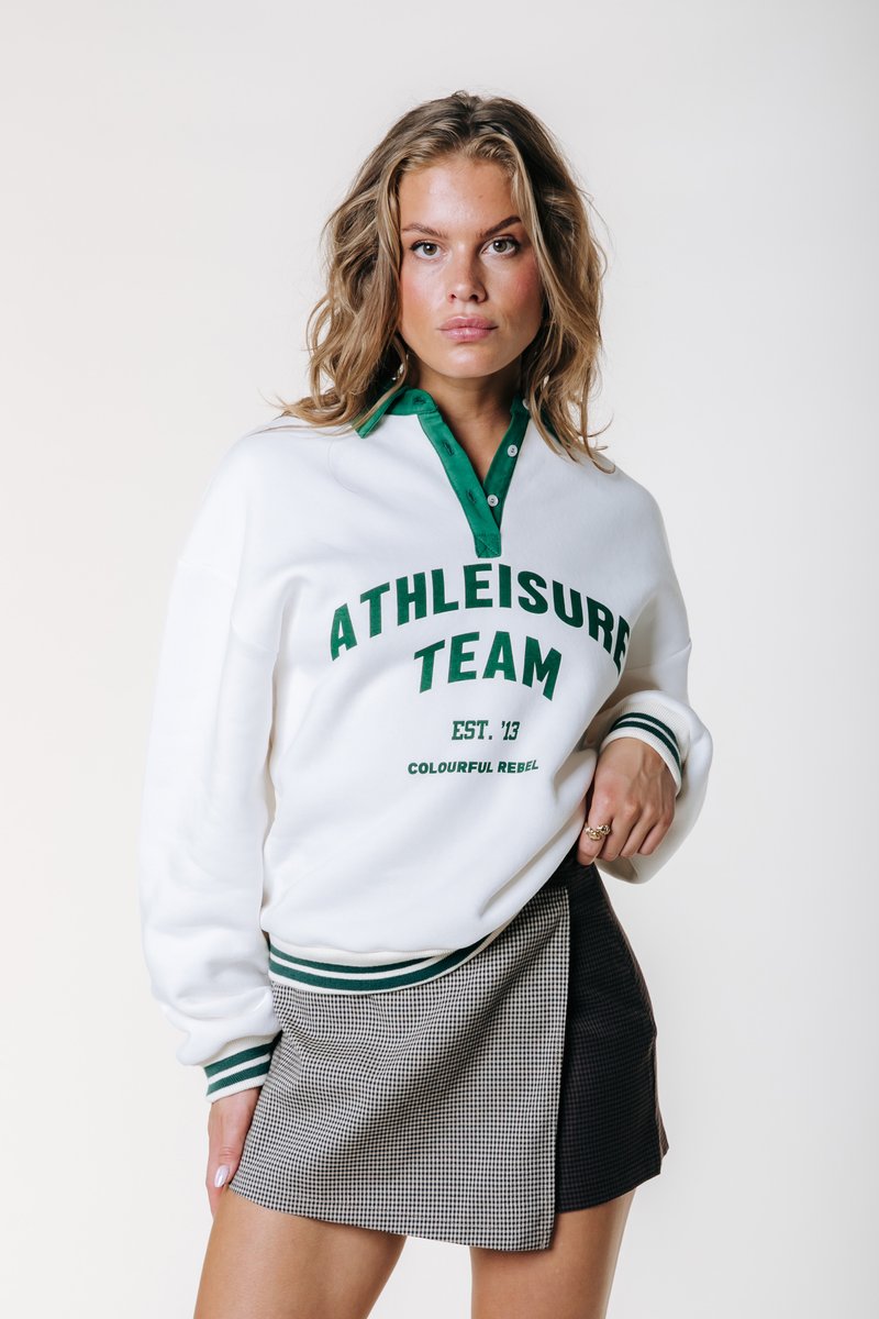 Λευκή μπ sweatshirt με πράσινο λαιμό και κείμενο "ATHLEISURE TEAM" σε συνδυασμό με φούστα σε μαύρο-άσπρο καρό. Διαθέτει ριγέ μανσέτες.