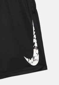 Zwarte stof met een vervormd wit Nike swoosh-logo in de onderste hoek van een kledingstuk, waarschijnlijk een korte broek of lange broek.