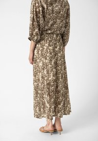 Abito midi marrone e crema a fantasia con una vestibilità comoda, vita arricciata e maniche a tre quarti, abbinato a sandali con tacco di colore chiaro.