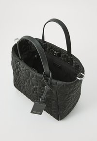 Black quilted handbag with smooth leather handles, a spacious interior, and a brand tag. Features a heart pattern and silver hardware accents.