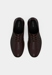 Καφέ δερμάτινα παπούτσια με κορδόνια, με λείο φινίρισμα, στρογγυλεμένη μύτη, αντίθετες ραφές και επωνυμασμένο πάτο. Κατάλληλα για επίσημες περιστάσεις.