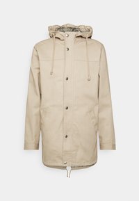 Giacca beige con cappuccio, bottoni automatici, cordino regolabile, due tasche laterali e orlo leggermente curvo. Realizzata in tessuto resistente.