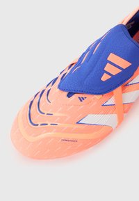 Scarpina da calcio arancione brillante con superficie texturizzata, accenti blu e strisce bianche. Presenta un design aerodinamico e il marchio HybridTouch.
