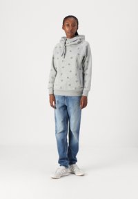 Gray hoodie with scattered floral print, drawstring hood, ribbed cuffs, paired with light blue denim jeans and white sneakers.