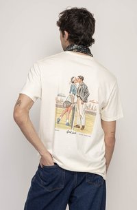 Kreminė medvilninė marškinė su retro teniso tema grafika ant nugaros, vaizduojanti porą, apsikabinusią, apsuptą korto scenos.