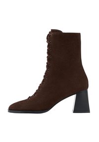 Stivale alla caviglia in suede marrone con punta affusolata, chiusura con lacci frontale e tacco a blocco. Il tacco presenta un accento testurizzato nero.
