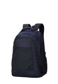 Sac à dos bleu marine en tissu texturé, avec une poche avant zippée et des poches latérales en mesh. Doté de bretelles réglables et d'une poignée supérieure robuste.