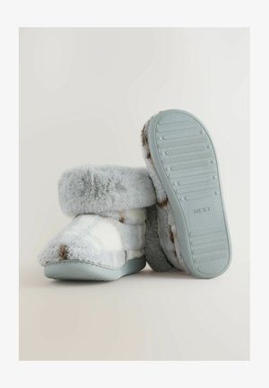 Zapatillas de felpa de color azul claro con un puño de piel sintética, adornadas con un patrón blanco y marrón, que cuentan con una suela de goma texturizada y un material suave y grueso.