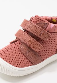 Sneaker rosa in rete con due strap a velcro, dettagli in suede testurizzato e una fodera interna a fantasia; suola in gomma bianca con dettagli rigati.