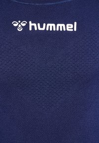 Mörkblå träningsskjorta med texturerat meshmönster, med vit "hummel"-logotyp på övre bröstområdet. Mjuk tygkomposition.