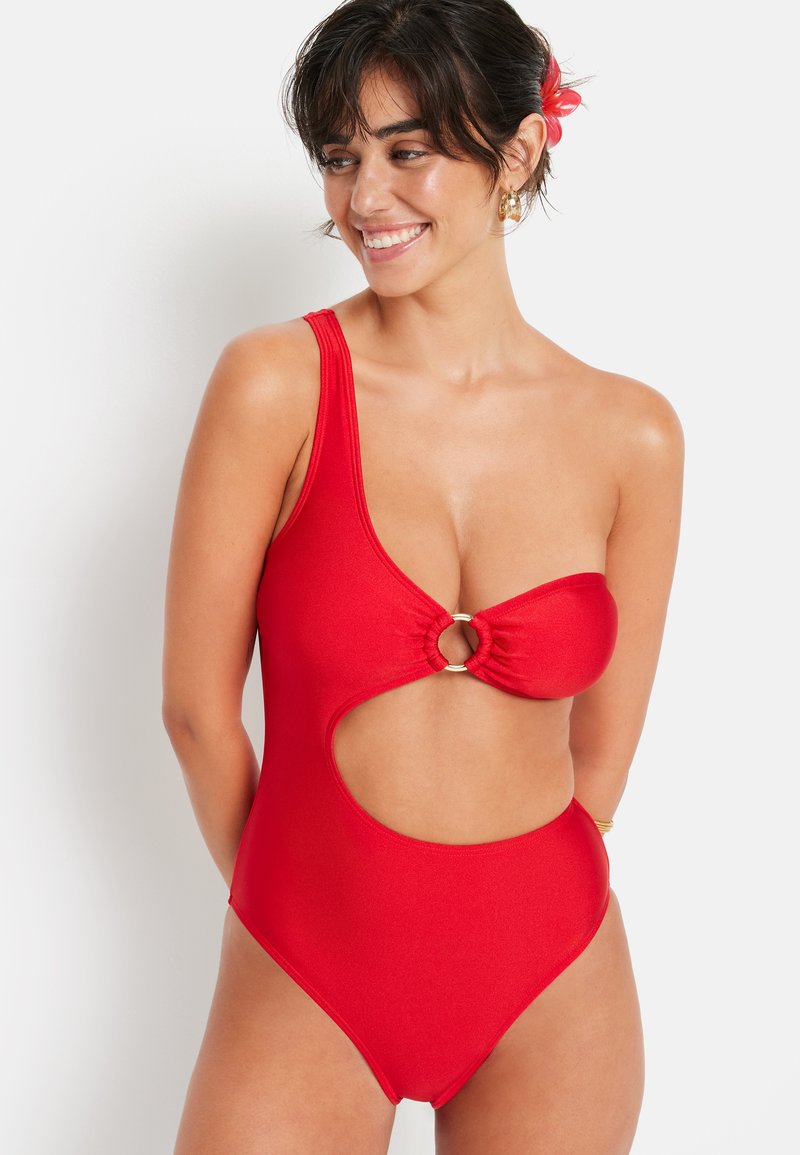 Maillot de bain une pièce rouge avec une seule bretelle et un design découpé. Il présente un anneau circulaire central et un tissu texturé.