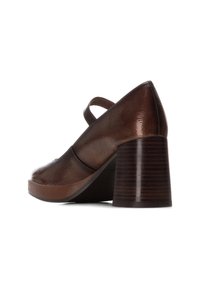 Scarpa con tacco in pelle marrone, con una finitura testurizzata, punta arrotondata, una fascia sulla parte superiore e un tacco in legno spesso e rigato.