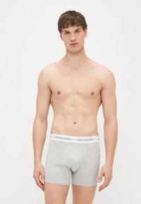 Harmaat, tiukasti istuvat puuvillaiset boksershortsit, joissa on valkoinen joustava vyötärönauha ja "ONLY&SONS"-logo. Minimalistinen muotoilu, pehmeä tekstuuri.