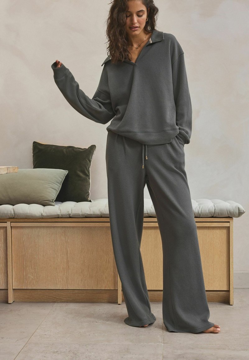 Dark gray loungewear set featuring a loose-fitting pullover with a collar and matching wide-leg pants made from soft, textured fabric.