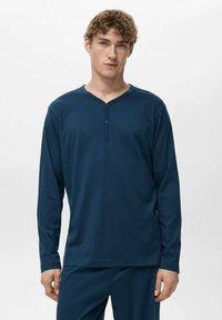 Camiseta henley de manga larga azul marino con escote en V, tapeta con dos botones y cuello acanalado, confeccionada con una tela suave y texturizada.