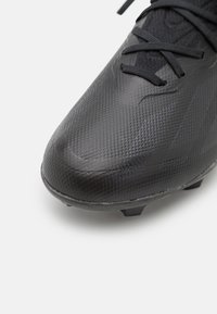 Schwarzer Fußballschuh mit oberer Schicht aus strukturiertem Synthetik, schlankem Design und Schnürverschluss. Verfügt über eine geformte Sohle mit ausgeprägten Stollen.