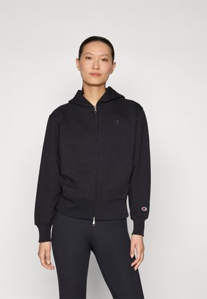 Felpa nera con zip realizzata in morbido cotone. Presenta un cappuccio, polsini a costine e un piccolo logo ricamato sul petto.