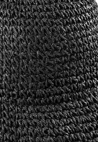 Czarna, tkana tkanina o strukturalnej powierzchni, z ściśle splecionymi włóknami. Materiał wydaje się trwały i elastyczny.