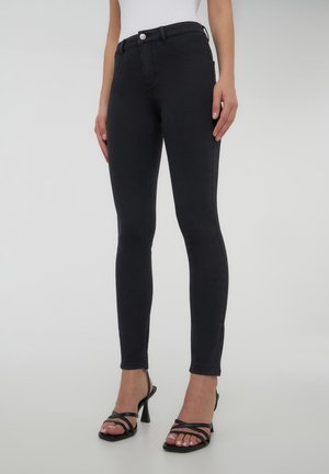 Jeans skinny neri in denim, con vita alta e una consistenza liscia. Il design include tasche anteriori e posteriori, con un bottone in metallo.