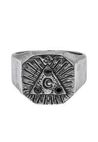 Anello in tonalità argento con un motivo triangolare, raggi incisi, una 'G' centrale e tre accenti in pietra nera su una superficie texturizzata.