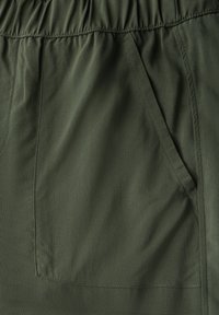 Groene stof met een gladde textuur, voorzien van een elastische tailleband en een zijzak. Het ontwerp is eenvoudig en functioneel.