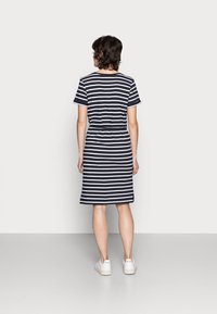 Gestreßtes T-Shirt-Kleid aus Baumwolle in Marineblau und Weiß mit kurzen Ärmeln und einem Taillenzug, verfügt über einen knielangen Saum und seitliche Schlitze.