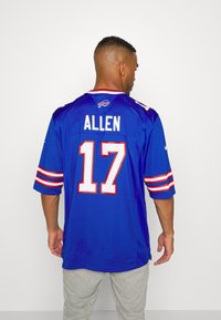 Camisa de futebol azul com mangas curtas, acentos em vermelho e branco, nome "ALLEN" e número "17" impressos nas costas. O tecido parece leve.