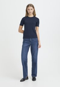 T-shirt en coton bleu marine à manches courtes associé à un jean bleu coupe droite. La tenue présente une coupe classique avec une texture simple et lisse.